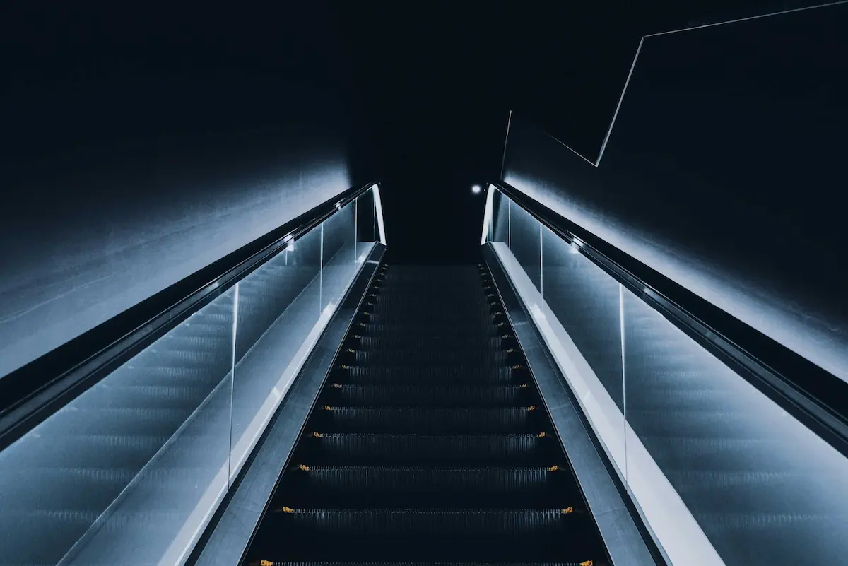 Illuminated escalator in dark space.