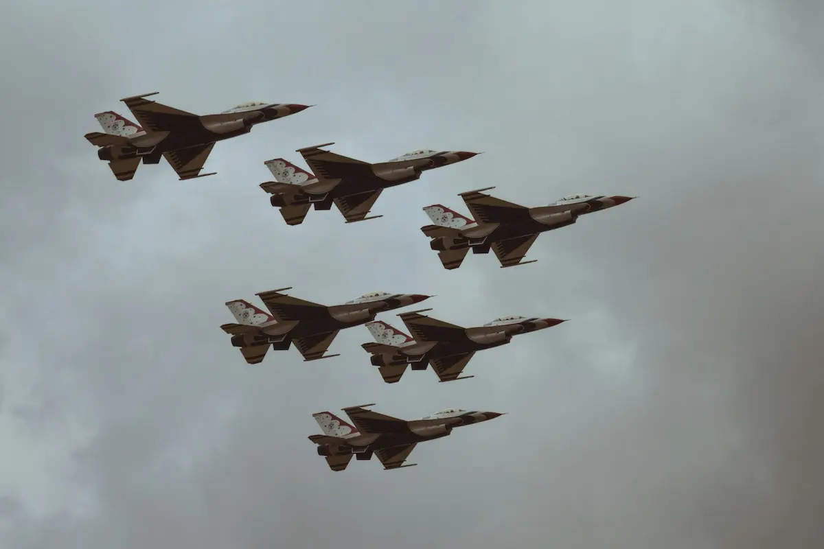 Six fighter jets flying in formation against cloudy sky.