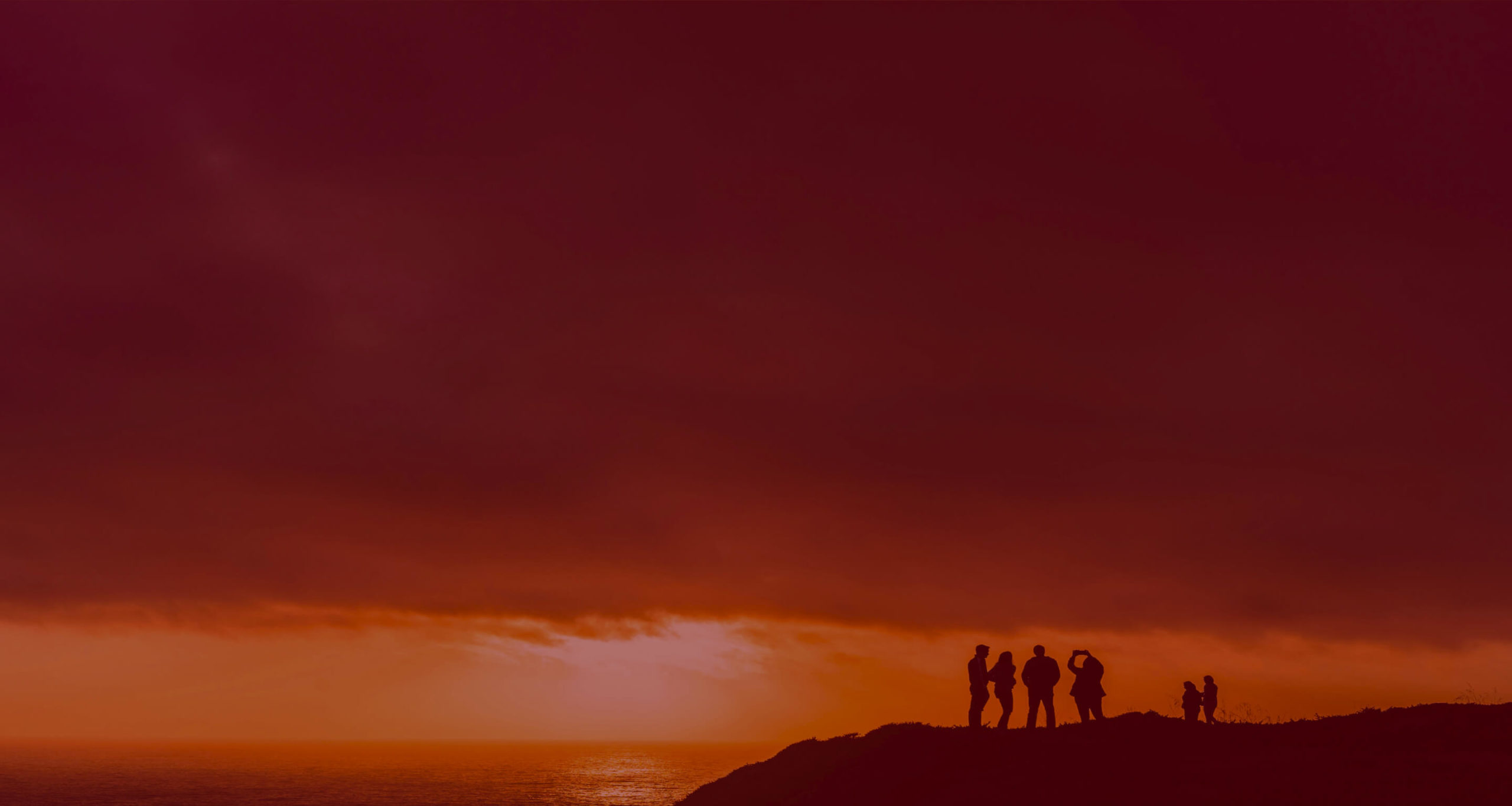 Silhouetted people on hill at sunset
