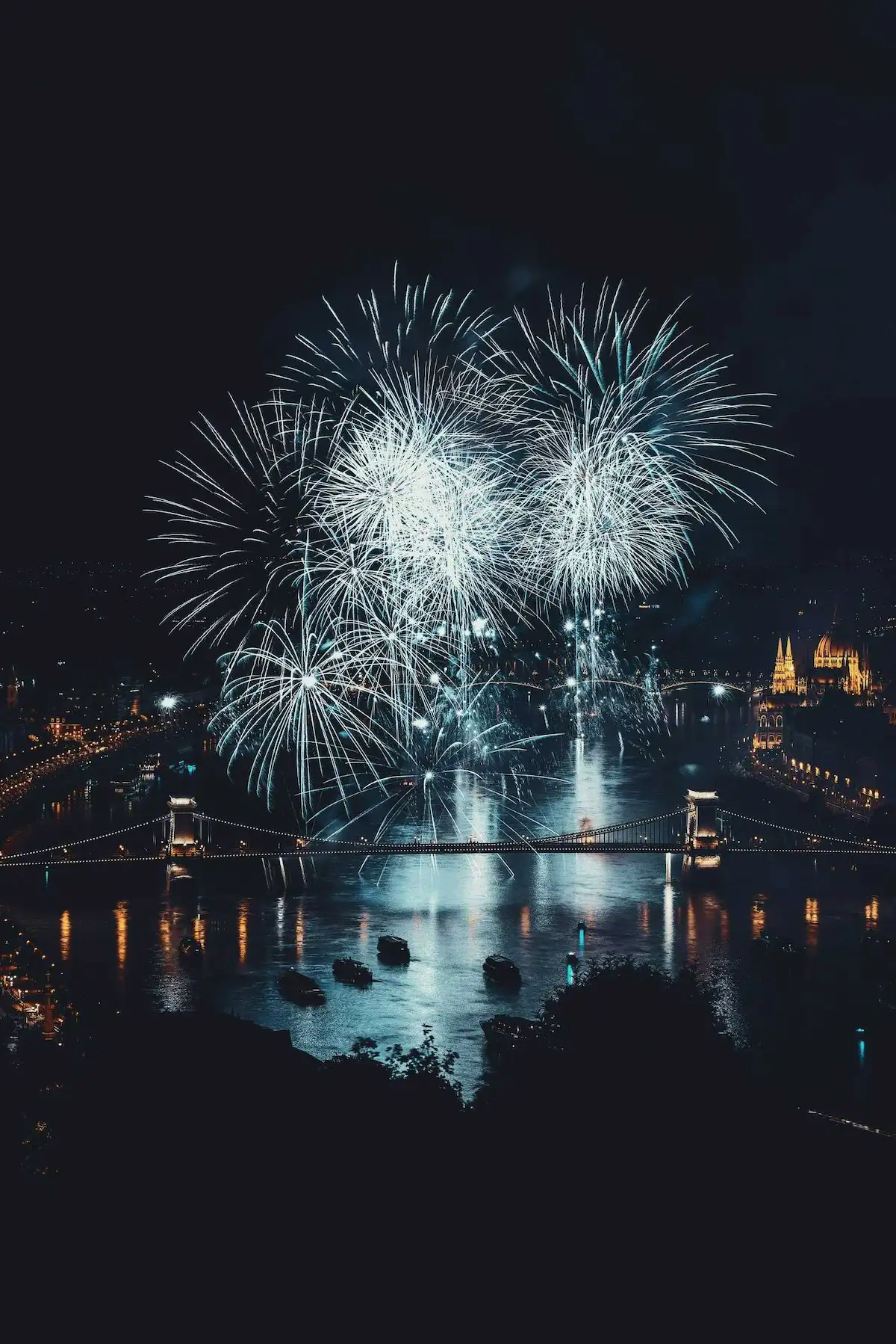 Fireworks over a city bridge at night.