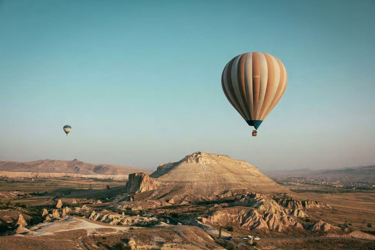 Hot air balloons over rocky landscape at sunset.